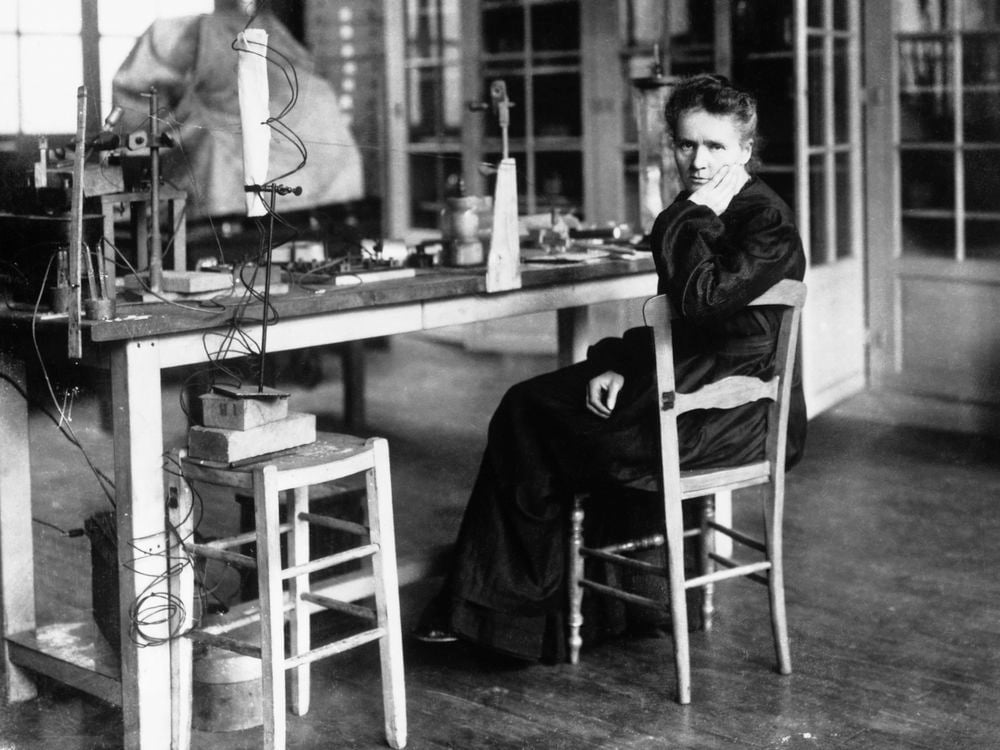 Black and white photo of a woman sitting in a chair in a laboratory