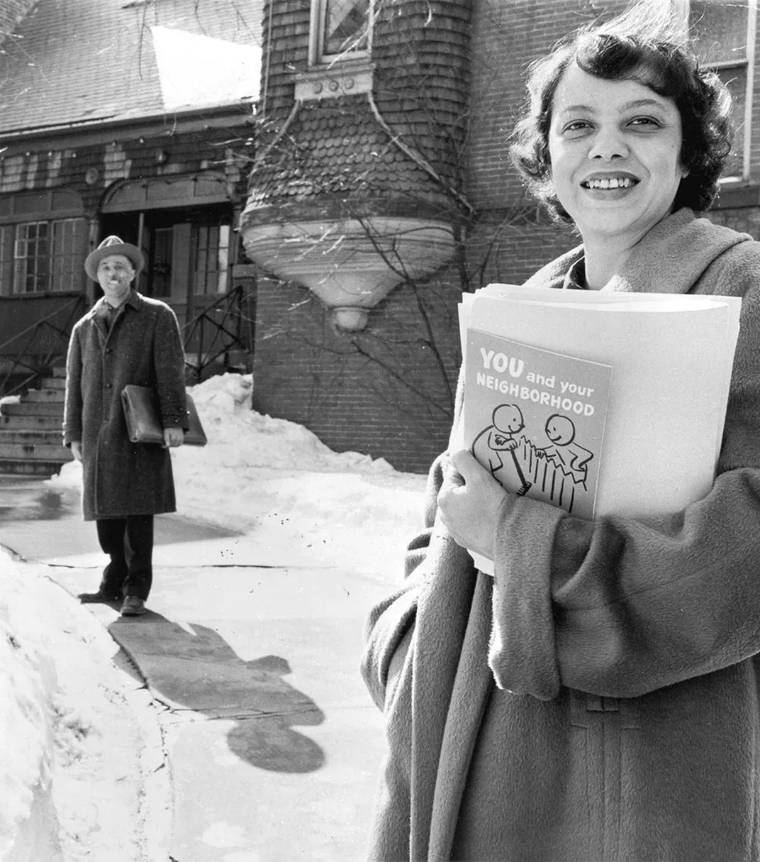 A man and women smiling at camera standing outside of brick building in snow