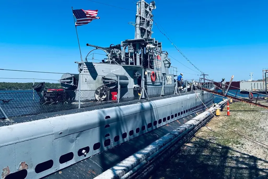 A submarine above the water with a ramp connecting it to land