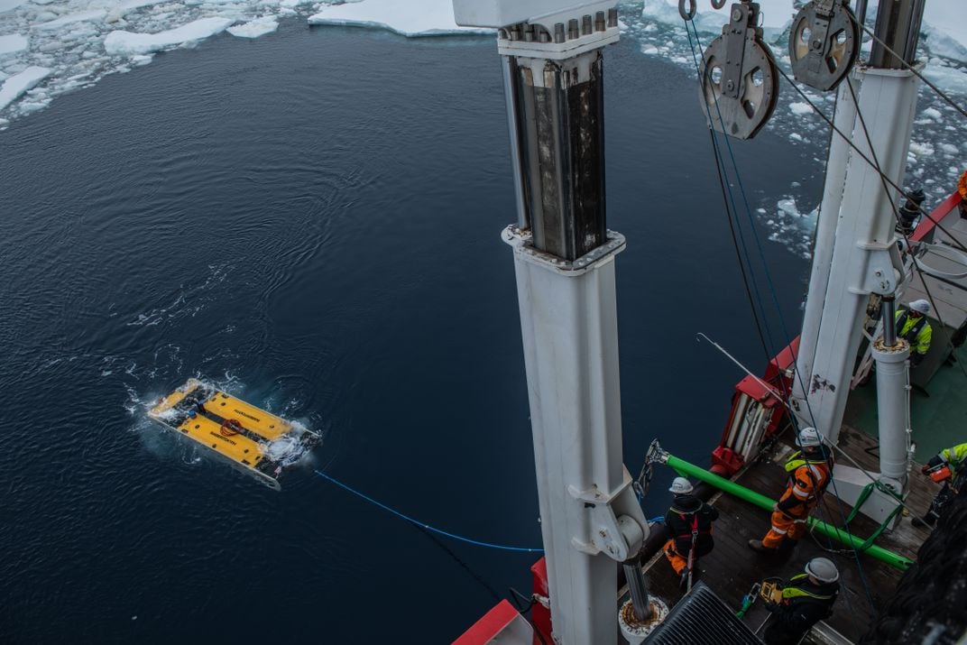 A view of a small submersible craft being lowered into icy water