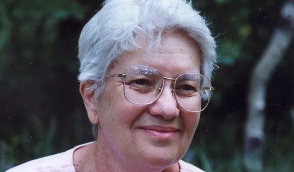 Vera Rubin in front of a green wooded area.