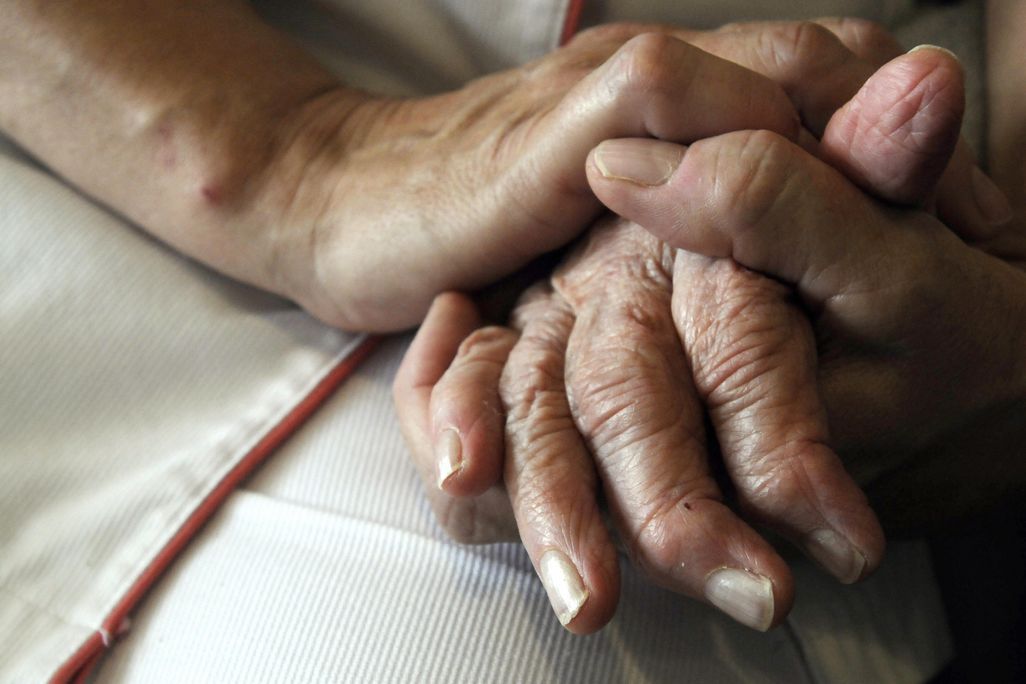 A nurse's hands hold those of an older person with Alzheimer's