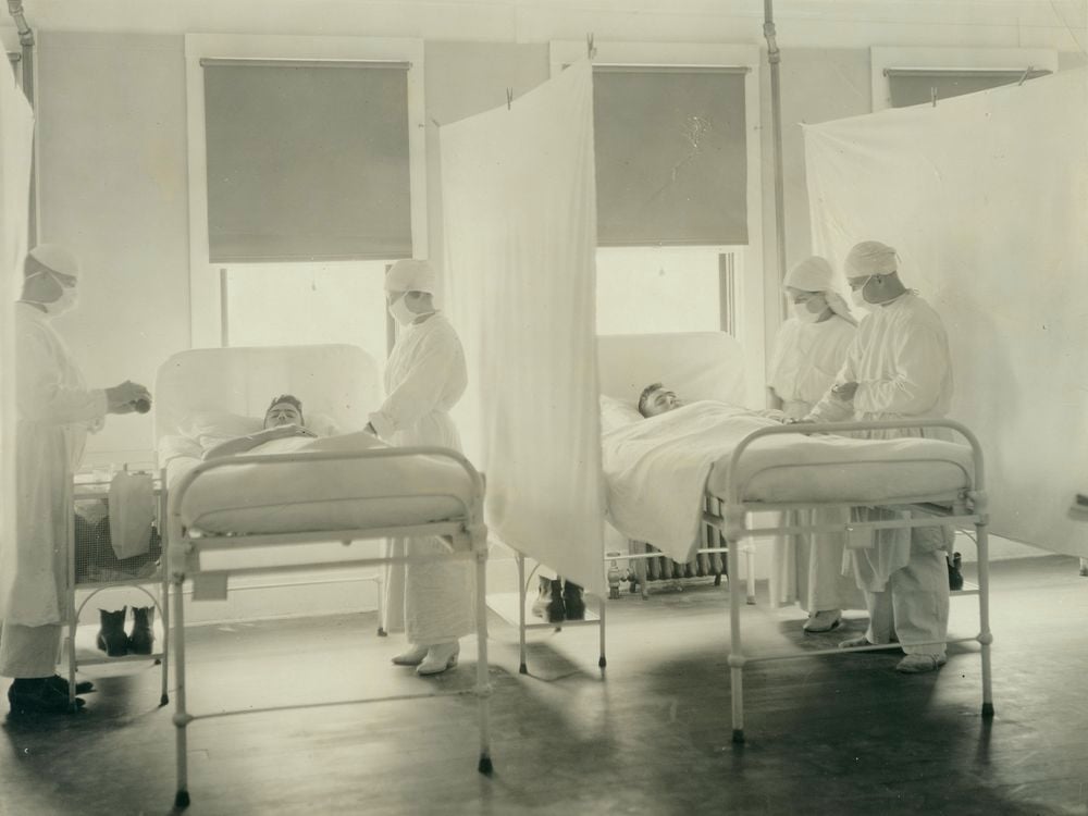 A black and white photograph of patients being treated by nurses during the 1918 influenza pandemic in a ward