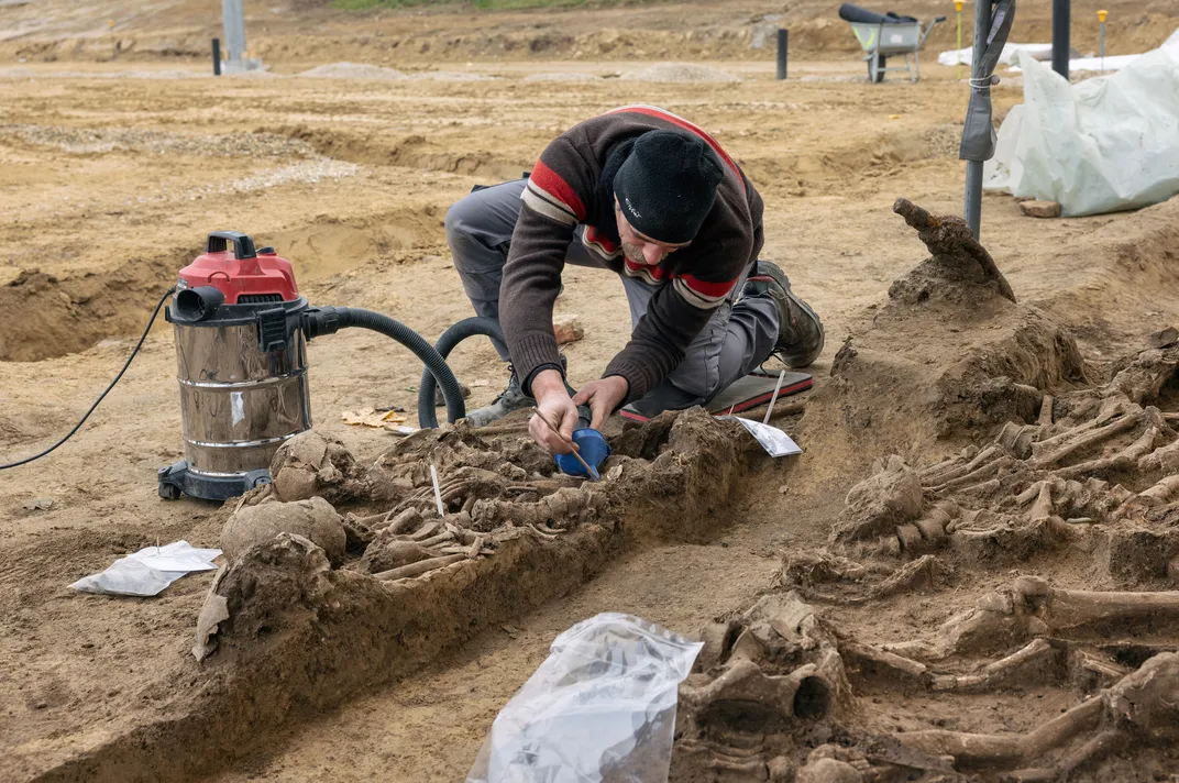An archaeologist examines a skeleton found in the mass grave.
