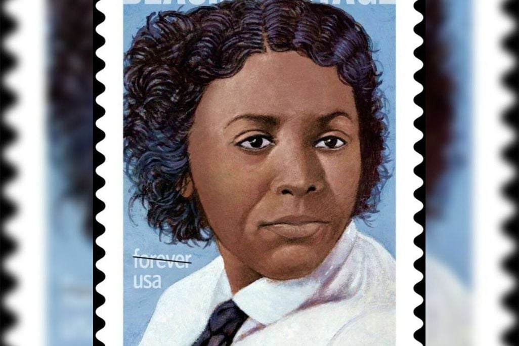 A stamp featuring a portrait of Edmonia Lewis, a Black woman with cropped wavy hair in a white shirt and black tie, on a blue background