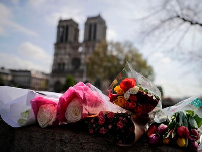 Flowers are laid on a bridge in front of the Notre-Dame-de Paris Cathedral in Paris.