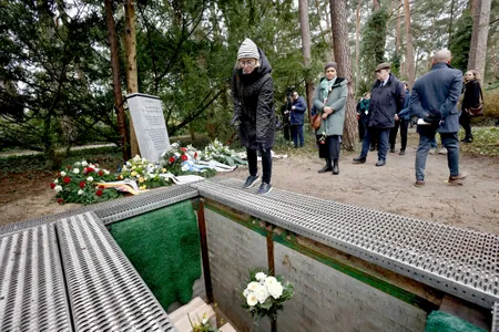A woman throws flowers on the boxes containing human remains at Waldfriedhof cemetery.