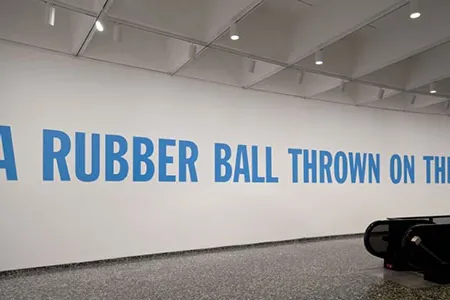 Lawrence Weiner's "A RUBBER BALL THROWN ON THE SEA, Cat. No. 146" is displayed at the Hirshhorn Museum in blue, sans-serif lettering. Weiner was open to the seven words being produced in any color, size or font.