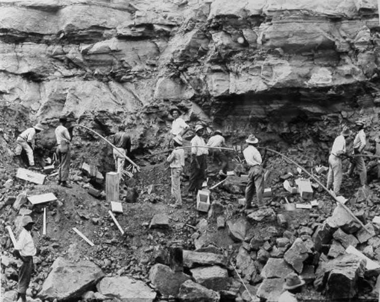 Loading shot holes with dynamite to blast a slide of rock in the west bank of the Culebra Cut, February 1912