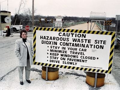 Marilyn Leistner, who was the last mayor of Times Beach, stands next to a caution sign erected in front of the town in 1991, not long before the town was bulldozed and buried.