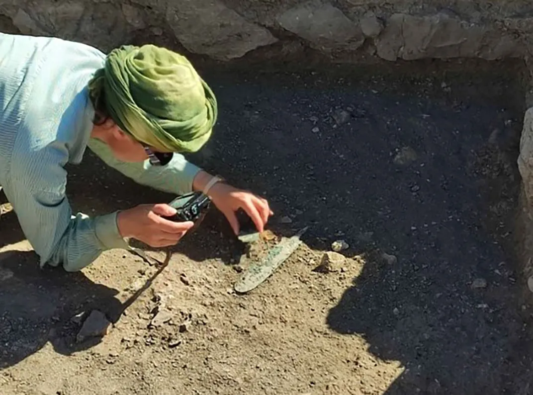 archaeologist examining rocks at dig site
