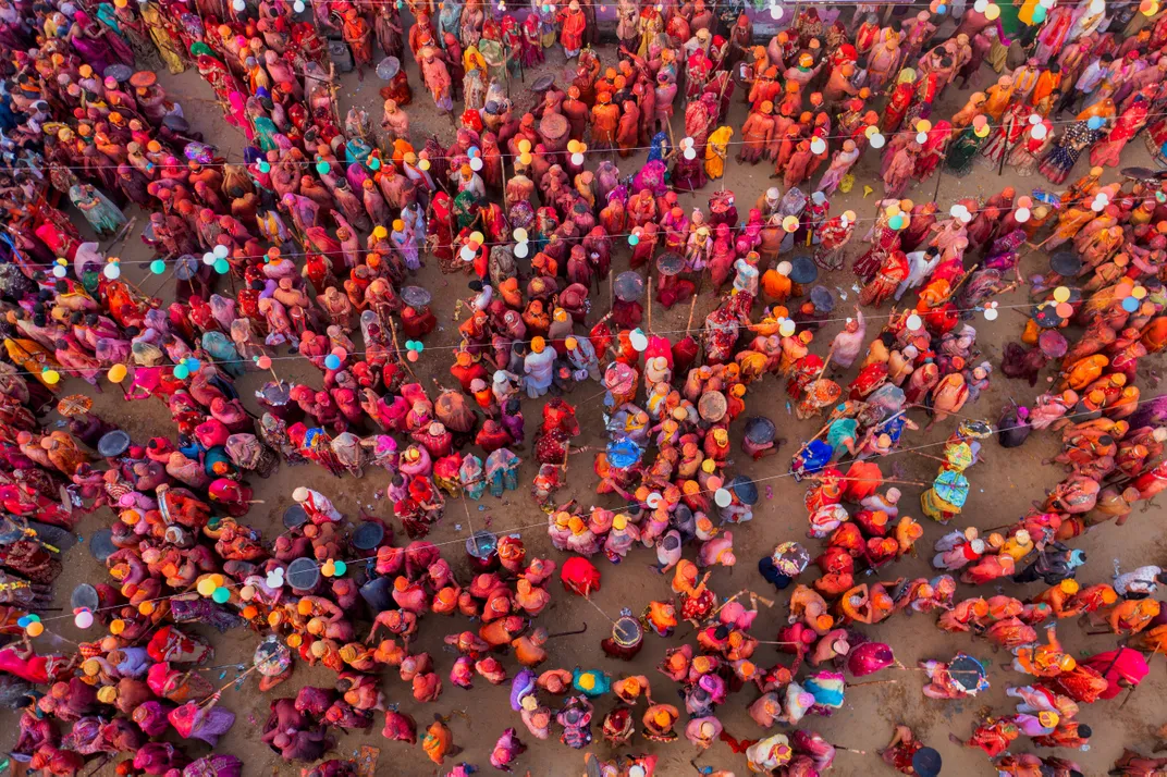 An aerial view captures crowds of color-clad celebrants enjoying Holi