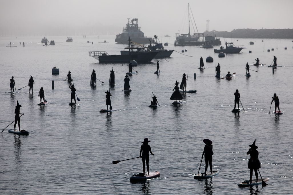 Silhouettes of people dressing as witches on standup paddleboards