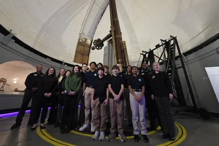 A group smile in front of the Great Refractor telescope