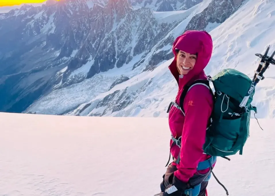 Preet smiles in front of mountains with a pack on her back