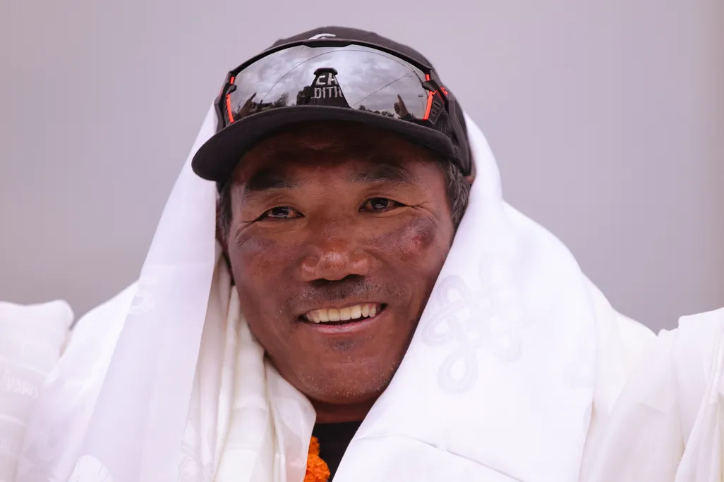 A man wearing a hat with glasses on them smiles