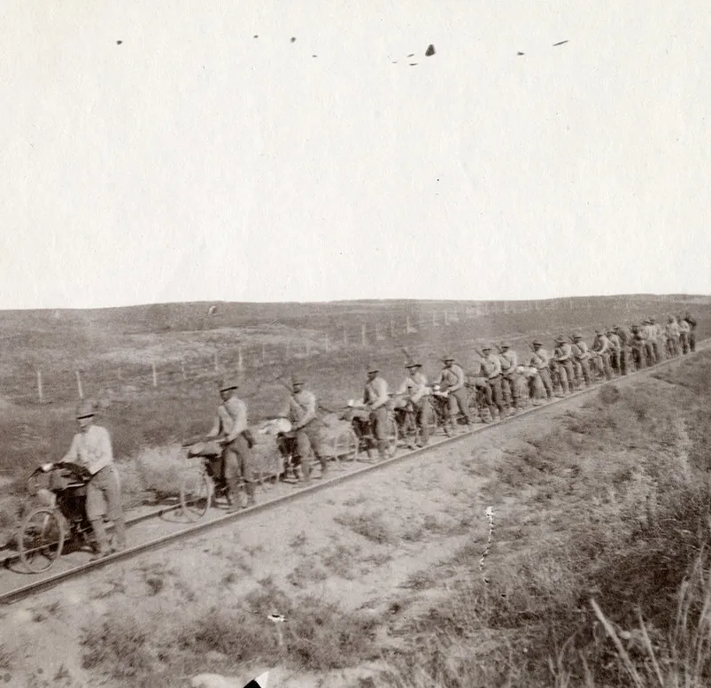 Soldiers walk their bikes along railroad tracks