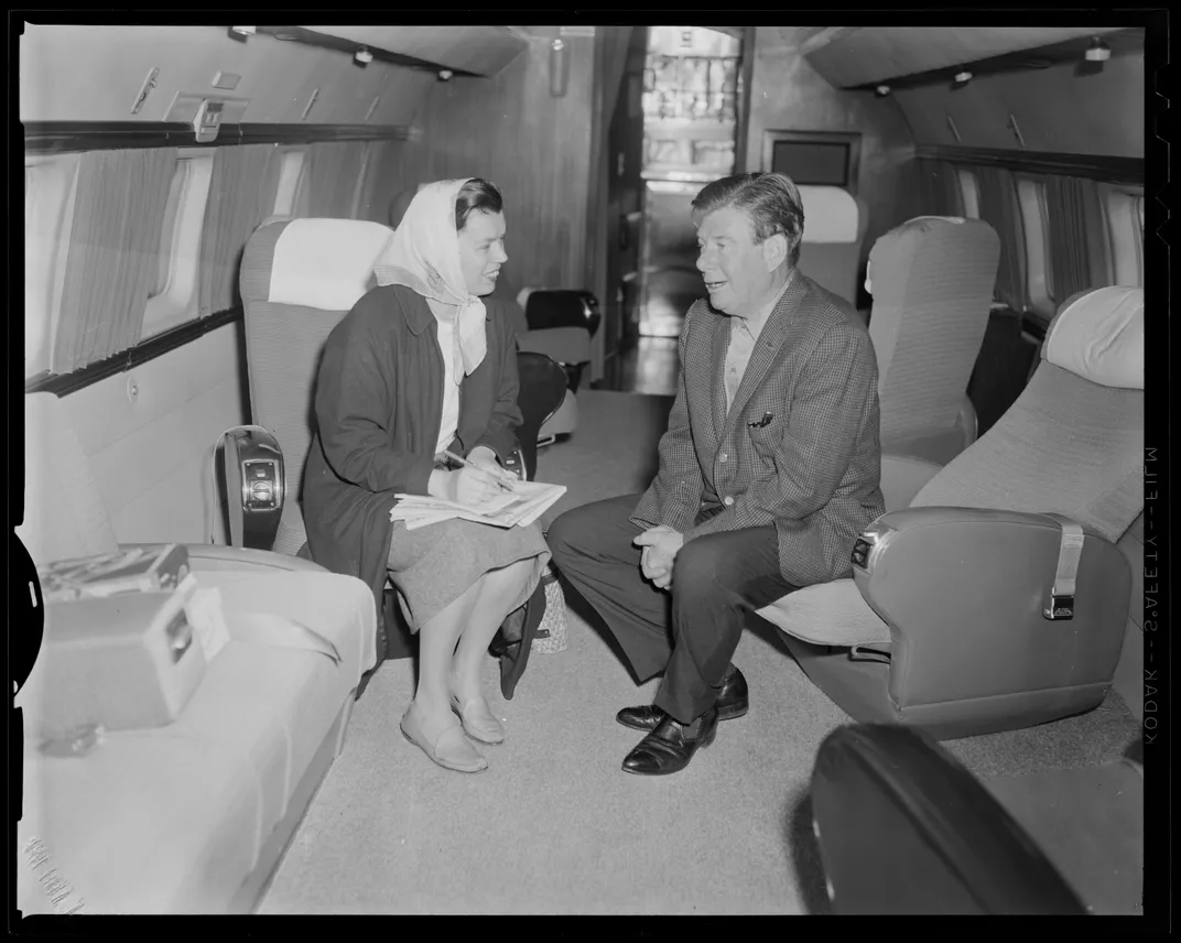 Arthur Godfrey and Loretta McLaughlin talking on an airplane in September 1962