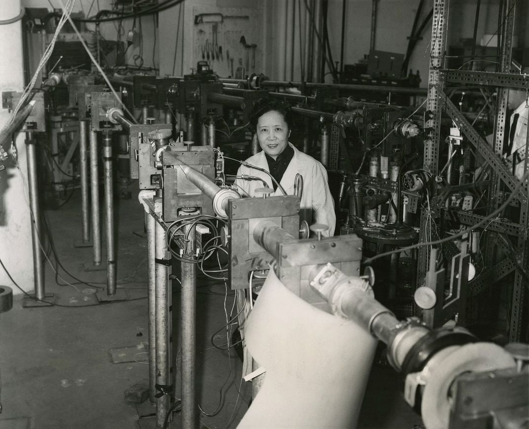 Chien-Shiung Wu is pictured in a labratory setting. She is wearing a white lab coat