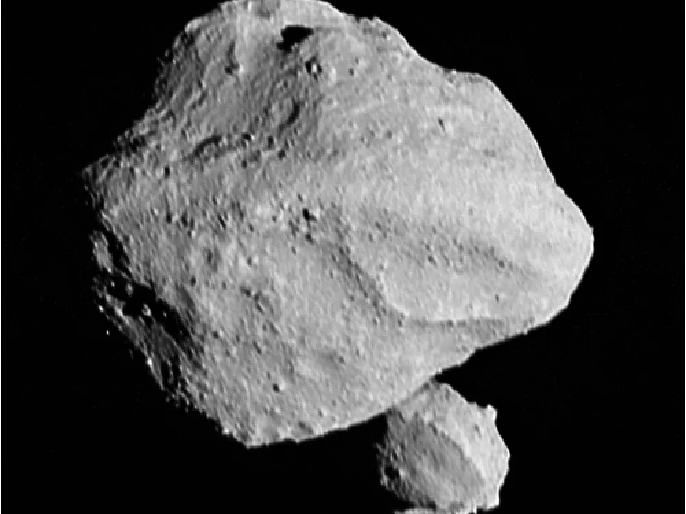 A black and white photo of an asteroid with a second smaller asteroid below and behind it
