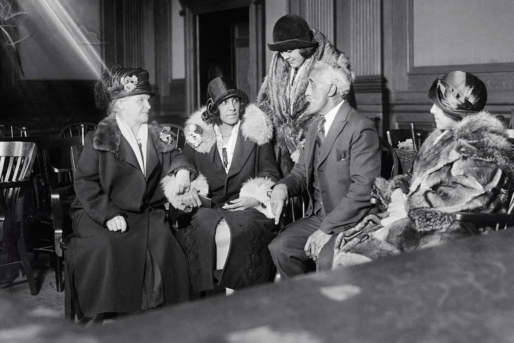 Alice Beatrice Rhinelander, née Jones (seated at center), looks at her father, George Jones, as they await the verdict in the Rhinelander v. Rhinelander ​​​​​​​case.