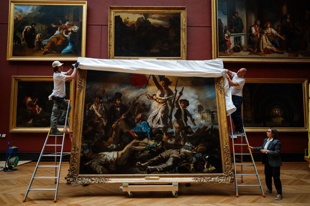 Workers taking protective sheet off a painting in an art gallery