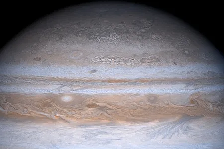 Jupiter's moon Io in orbit around the gas giant. Io is casting a dark shadow on Jupiter's atmosphere.