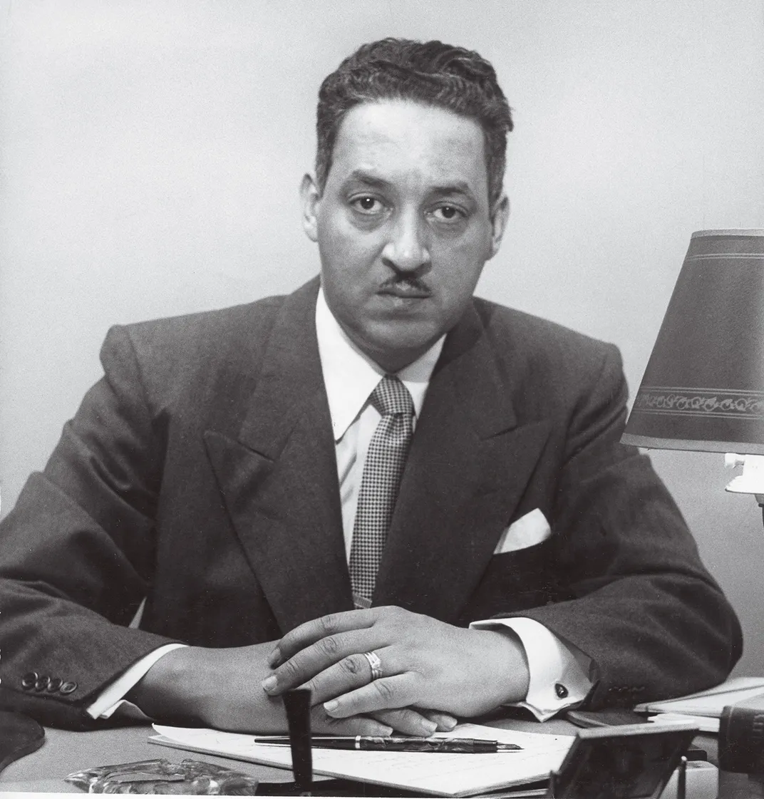 a portrait of a man in a suite sitting at a desk