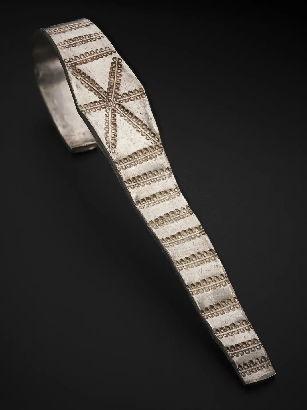 Silver arm band against a black backdrop