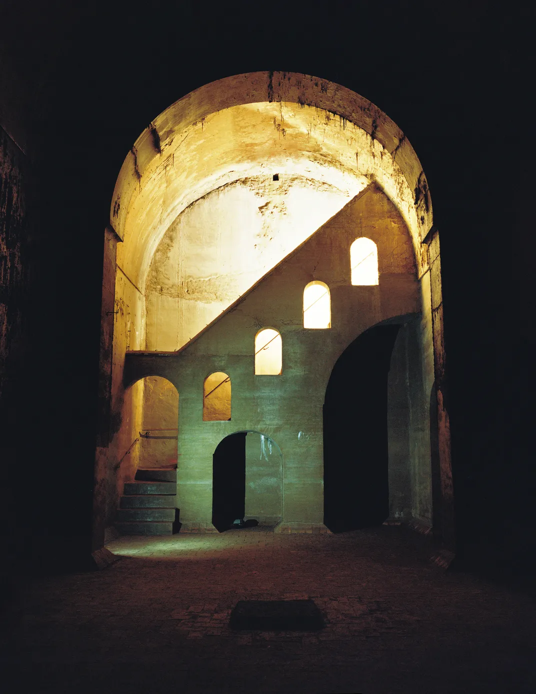 a dark underground passage shows an illuminated staircase