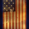 A piece of fabric has a design of alternating red and white stripes along with a dark blue rectangle featuring at least 14 white stars.