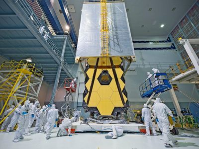 NASA technicians and engineers place a tent over the folded-up James Webb Space Telescope to protect it from dust and dirt once it leaves the "clean room" and proceeds to acoustic and vibrational testing.