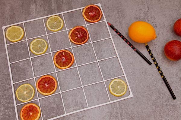 Playing games with kids in the kitchen. Lemon slices, red oranges, pencils and a whole lemon on a dark background. thumbnail