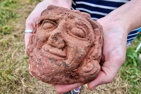 The carved head is made of red sandstone.