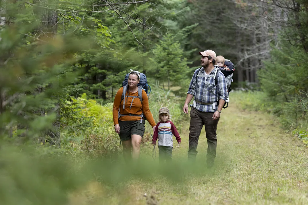 A family walking through green space with trees