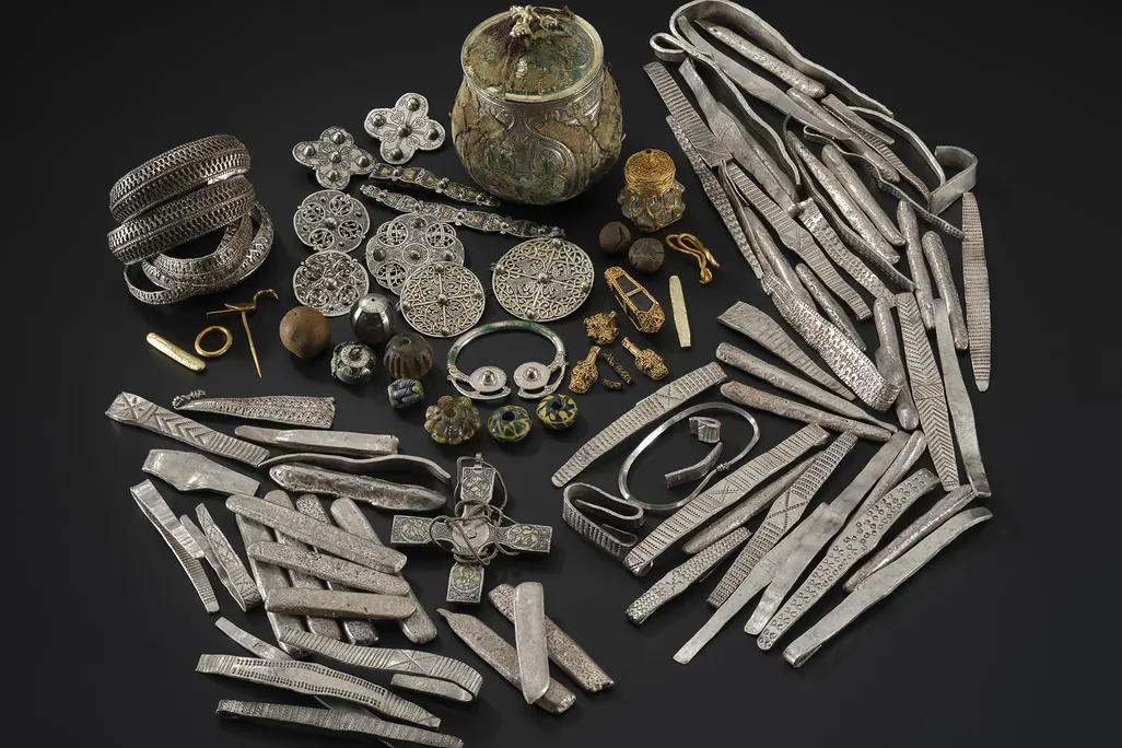A group of gold, silver and other artifacts against a black background