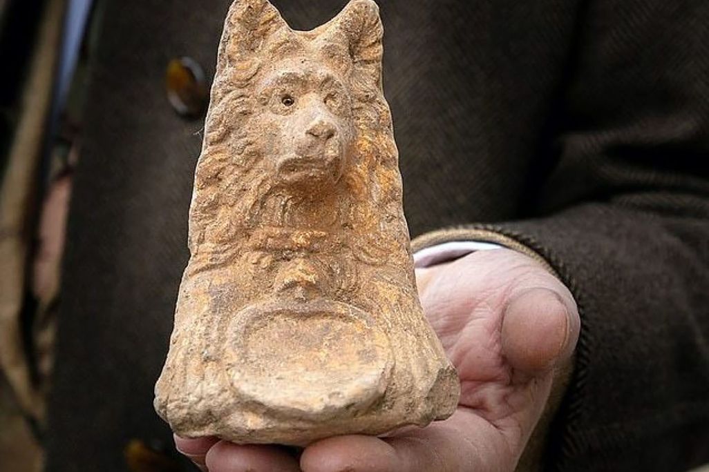 clay figure of dog with pointy ears, color with large emblem and long shaggy fur