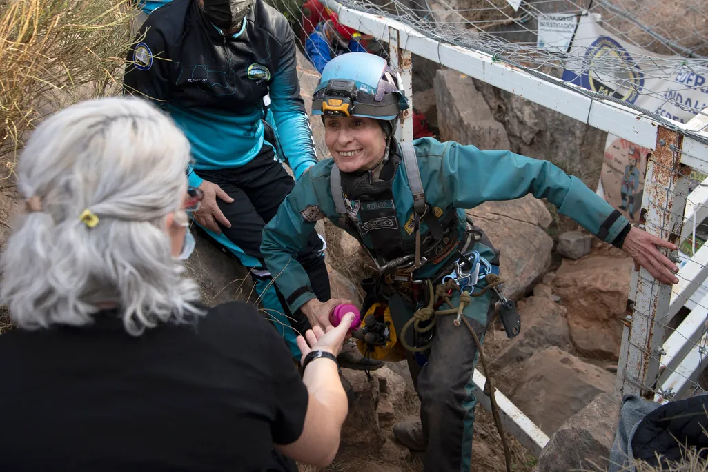 Woman wearing hardhat smiles and emerges from cave