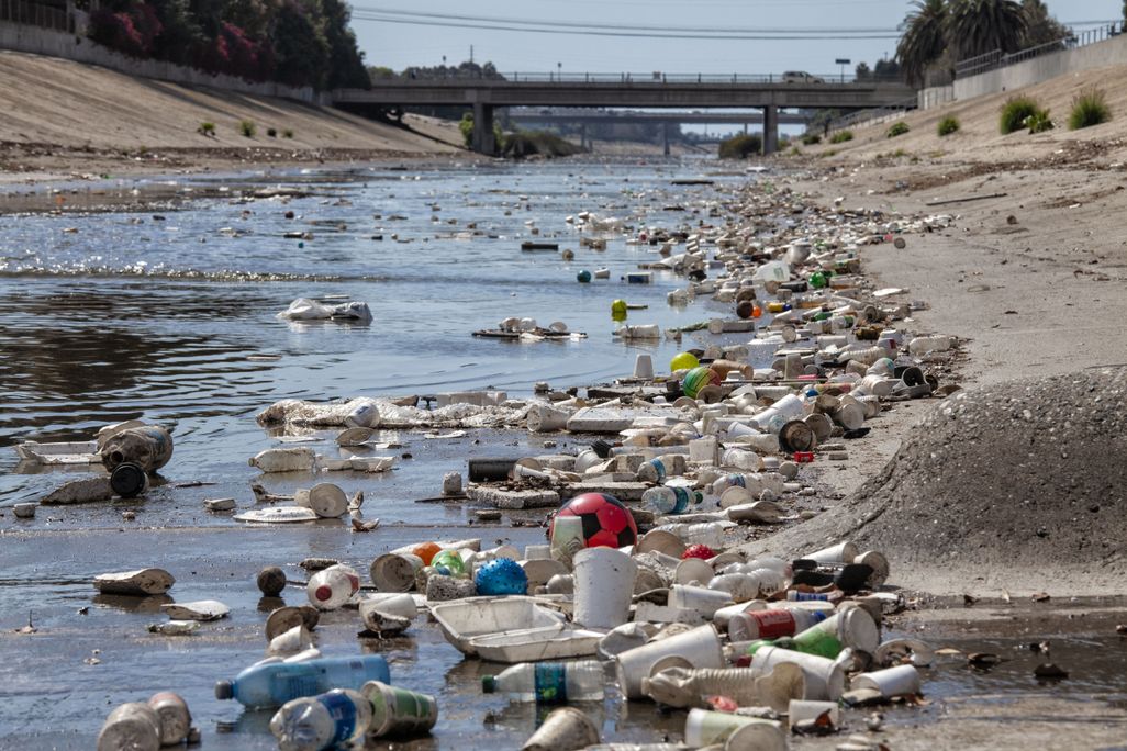 Large amounts of plastic trash like bottles in a channelized creek in Culver City, California.