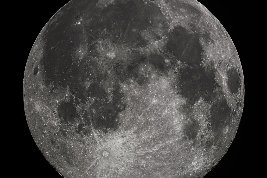An image of a full moon. The moon looks silver with grey sploches.
