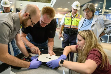 Staff remove the touchable moon rock’s mount while curator Priscilla Strain, second from right, looks on.
