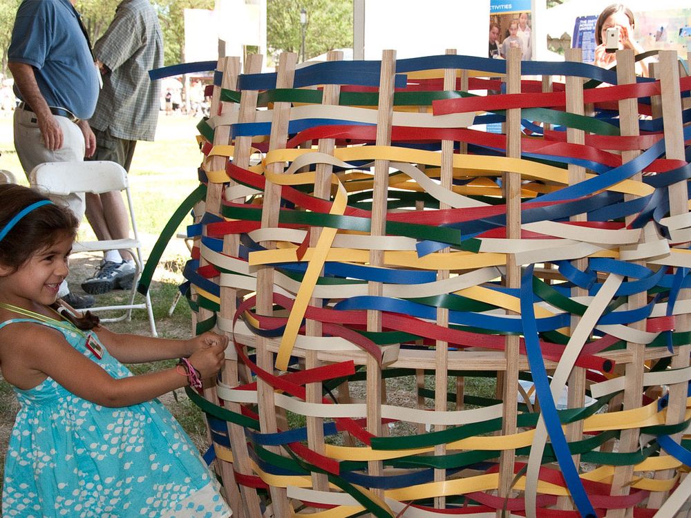 A young girl pulls strands on an oversized, multicolor basket.