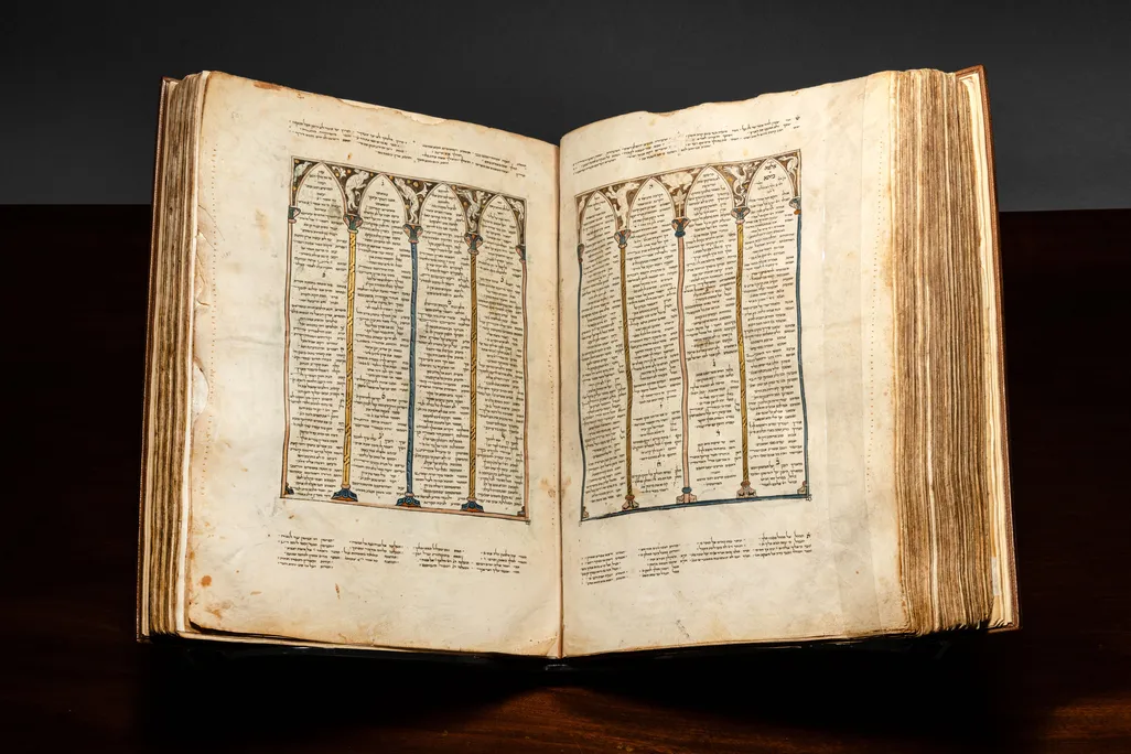Book with Hebrew writing open on a stand against a dark backdrop