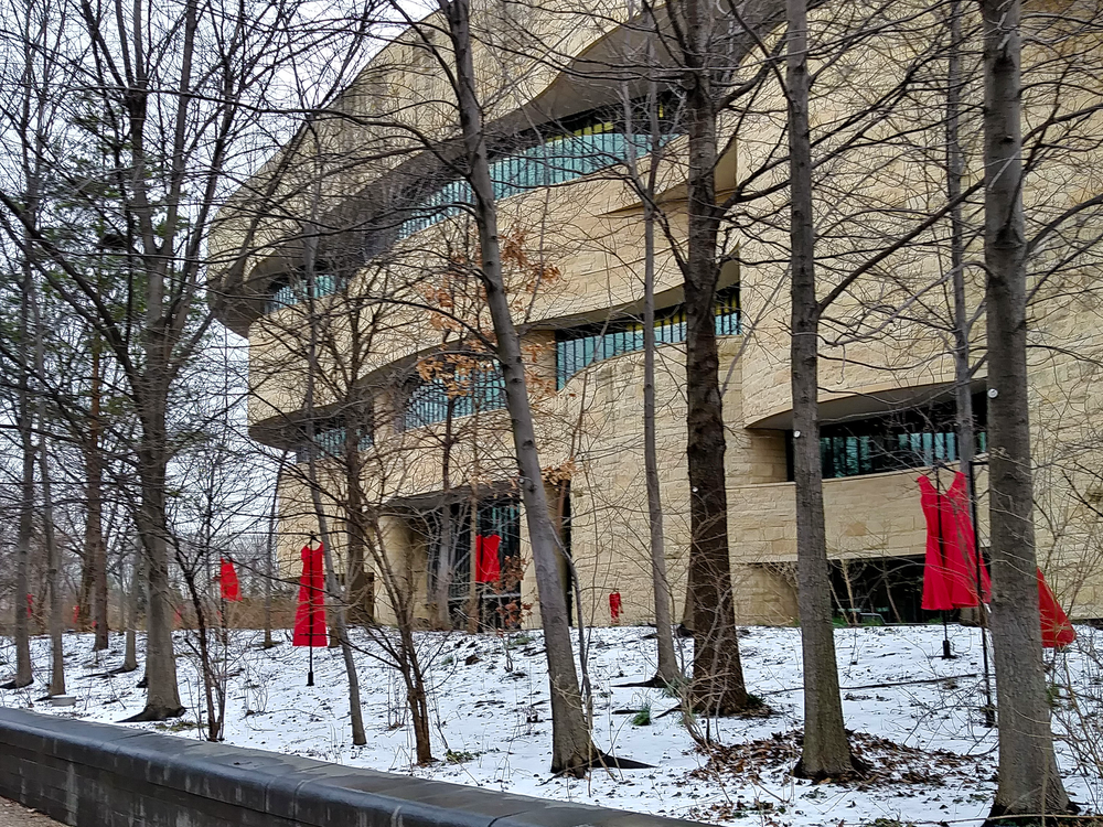 Red dresses displayed along the river walk of the National Museum of the American Indian in Washington, D.C., represent the crisis of missing or murdered Indigenous women and girls. Conceived by Canadian artist Jaime Black (Métis), 