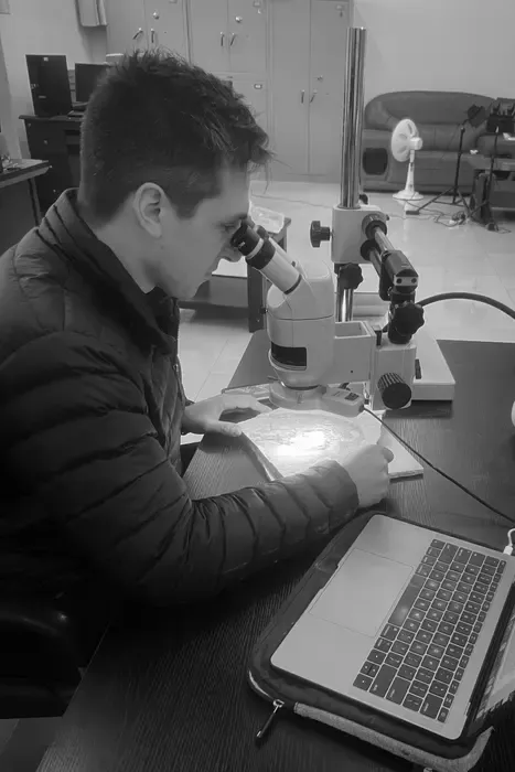 man looking through microscope in black and white