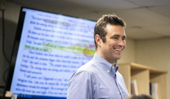 Man stands in front of screen with a chapter of a book on it and highlighted text