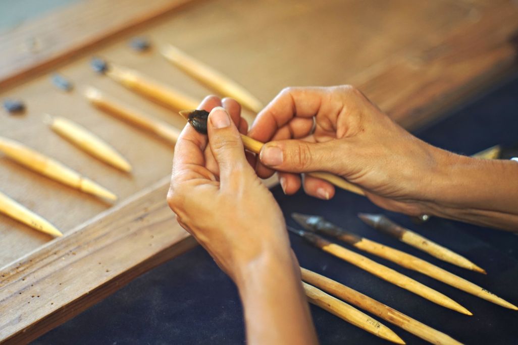Pair of hands holding an arrowhead on wooden dowel