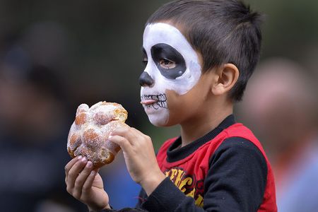A zombie enjoys a bite of pan de muertos at a Day of the Dead celebration in Atlanta, Georgia. 