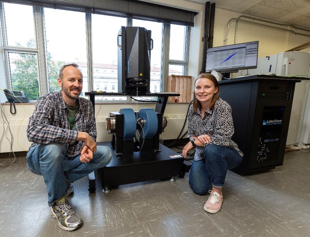 Two people next to a machine in a lab.
