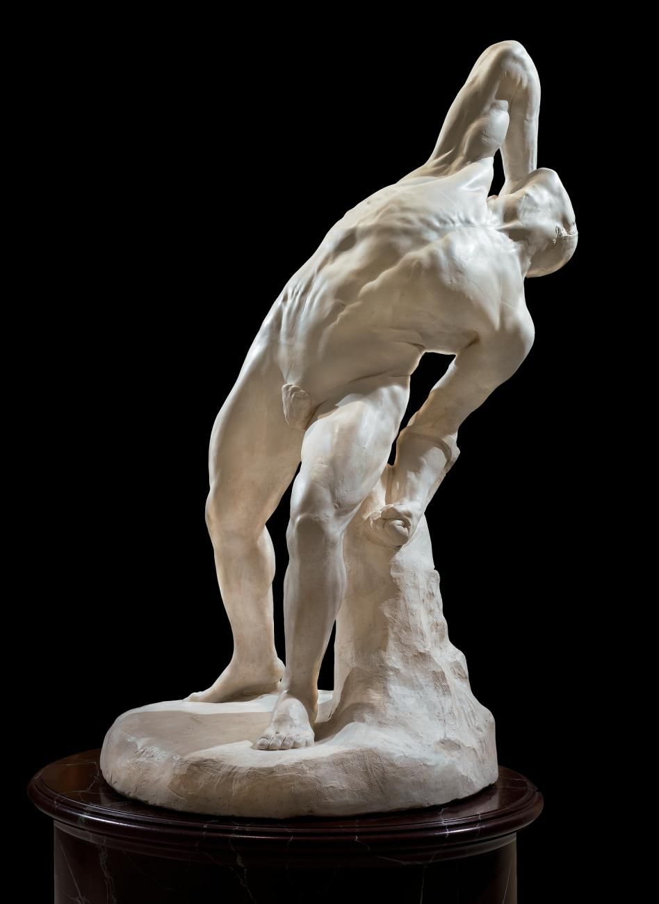 Statue of man leaning back over backward over a bolder 